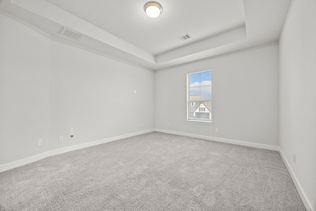 carpeted empty room featuring a tray ceiling