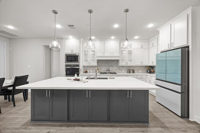 kitchen featuring white cabinetry, an island with sink, hanging light fixtures, and appliances with stainless steel finishes