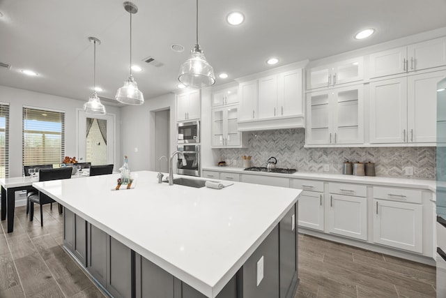 kitchen featuring pendant lighting, a center island with sink, and white cabinetry