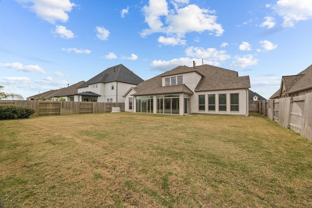 rear view of house with a sunroom and a yard