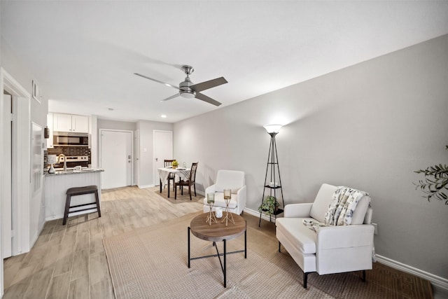 living area featuring ceiling fan, sink, and light hardwood / wood-style flooring