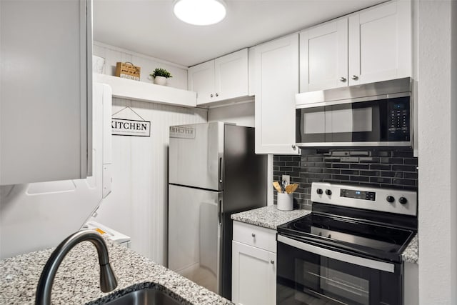 kitchen with light stone countertops, white cabinets, and stainless steel appliances