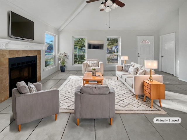 tiled living room featuring a tile fireplace, lofted ceiling with beams, and ceiling fan