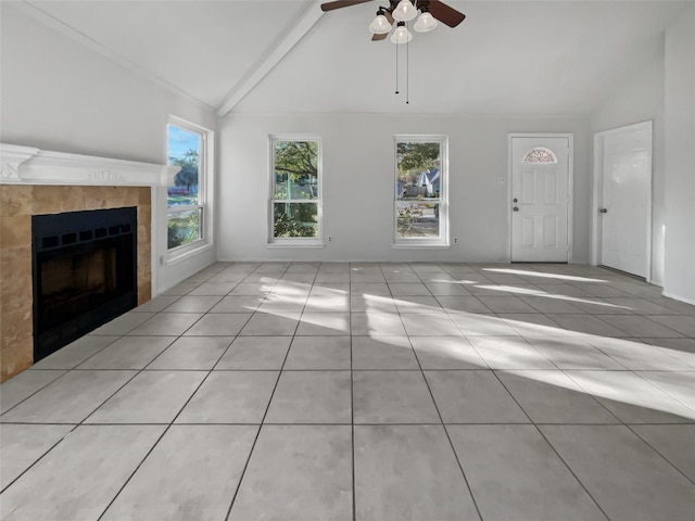 unfurnished living room featuring ceiling fan, a tile fireplace, vaulted ceiling with beams, and plenty of natural light