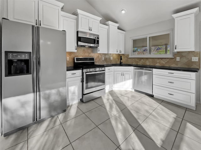 kitchen with sink, white cabinets, vaulted ceiling, backsplash, and appliances with stainless steel finishes