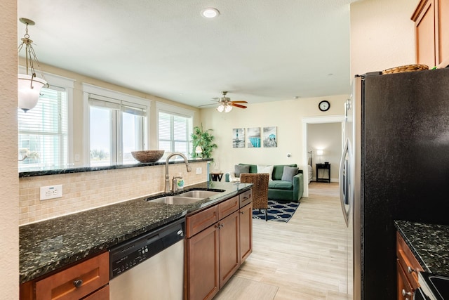 kitchen featuring appliances with stainless steel finishes, dark stone counters, sink, hanging light fixtures, and plenty of natural light