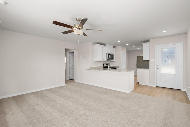 kitchen with white cabinets, light colored carpet, kitchen peninsula, and appliances with stainless steel finishes