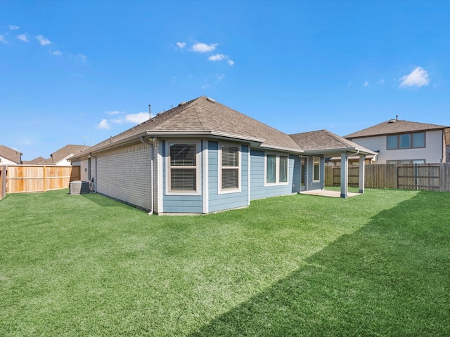 rear view of house featuring a lawn and central AC