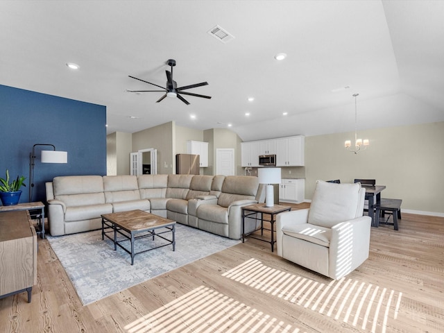 living room featuring ceiling fan with notable chandelier, light wood-type flooring, and lofted ceiling