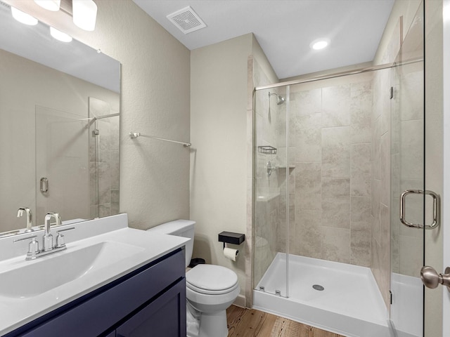 bathroom featuring vanity, hardwood / wood-style flooring, toilet, and an enclosed shower