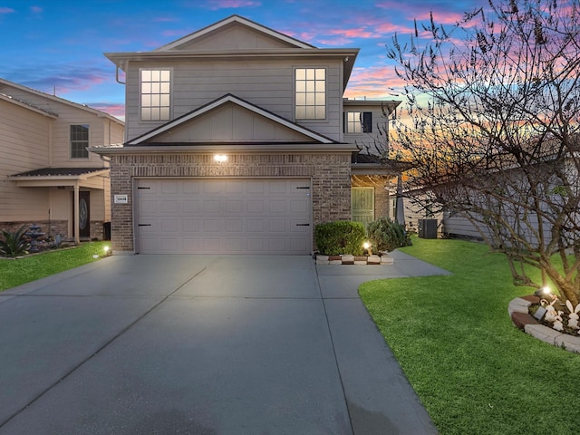 view of property featuring a lawn, central AC unit, and a garage