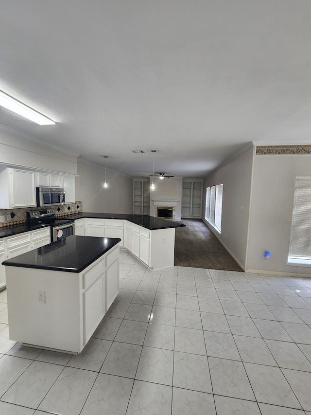 kitchen with white cabinets, crown molding, hanging light fixtures, appliances with stainless steel finishes, and a kitchen island