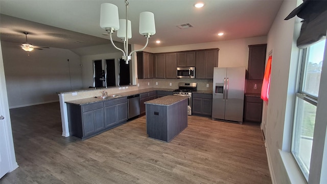 kitchen with a center island, kitchen peninsula, pendant lighting, decorative backsplash, and appliances with stainless steel finishes