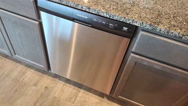 room details featuring light stone counters and stainless steel dishwasher