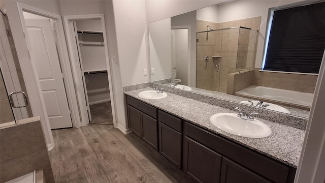 full bathroom featuring toilet, vanity, wood-type flooring, and shower with separate bathtub