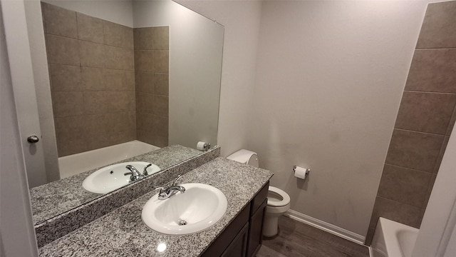 bathroom featuring hardwood / wood-style flooring, vanity, toilet, and a tub to relax in