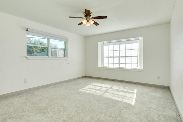 spare room featuring light carpet, a wealth of natural light, and ceiling fan