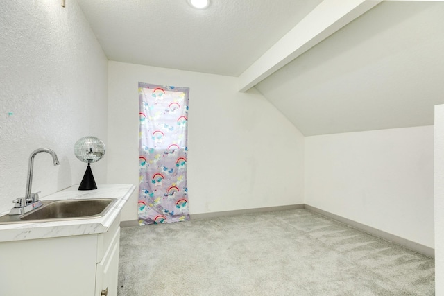 interior space with light carpet, sink, white cabinets, and lofted ceiling with beams