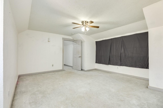 carpeted empty room with a textured ceiling, ceiling fan, and vaulted ceiling