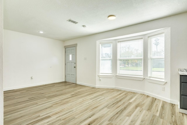 unfurnished living room with a textured ceiling and light wood-type flooring