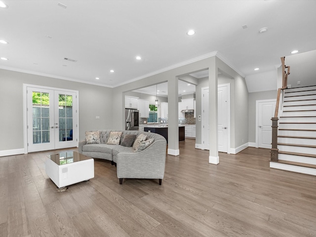 living room featuring french doors, ornamental molding, and light hardwood / wood-style flooring