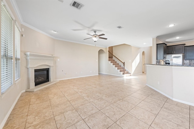 unfurnished living room with light tile patterned floors, ceiling fan, and crown molding