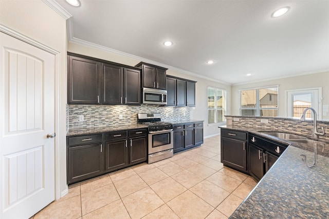 kitchen featuring sink, appliances with stainless steel finishes, dark stone counters, light tile patterned floors, and ornamental molding