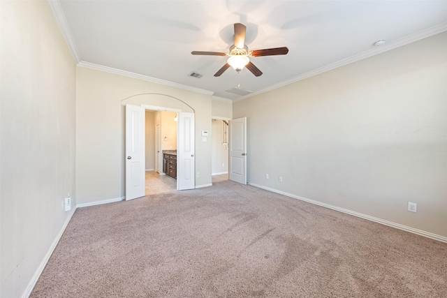 unfurnished bedroom featuring ceiling fan, light colored carpet, crown molding, and ensuite bath