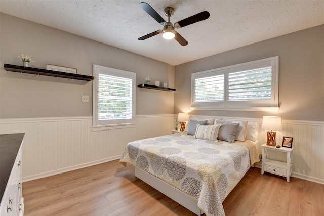 bedroom featuring a textured ceiling, light wood-type flooring, and ceiling fan