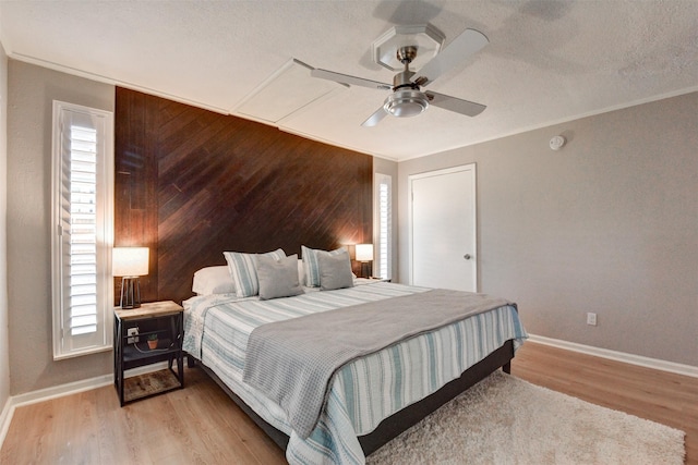 bedroom featuring multiple windows, light wood-type flooring, ceiling fan, and wood walls