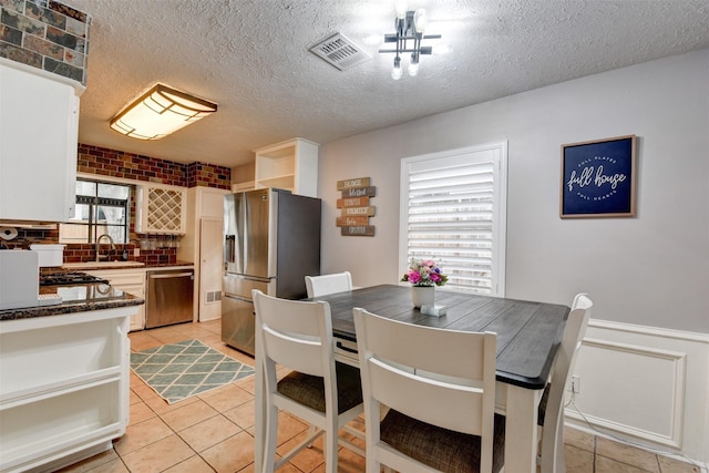 tiled dining space featuring sink and a textured ceiling