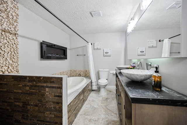 bathroom with a textured ceiling, vanity, a relaxing tiled tub, and toilet