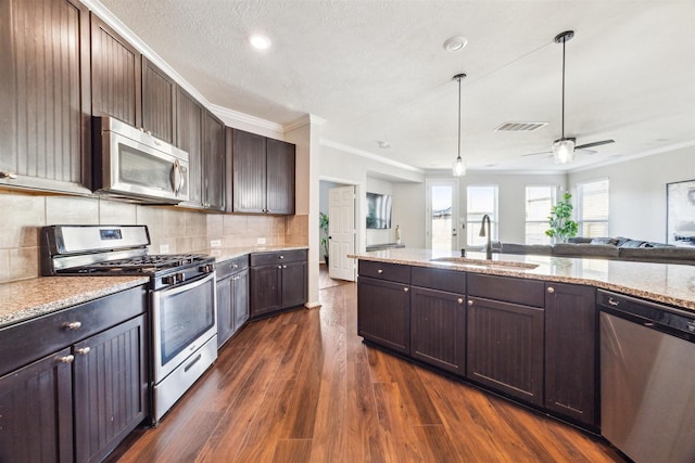 kitchen featuring sink, dark wood-type flooring, decorative backsplash, dark brown cabinets, and appliances with stainless steel finishes