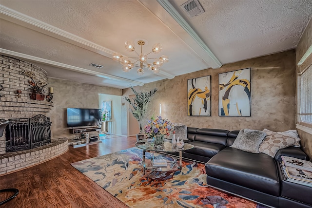 living room featuring a brick fireplace, beamed ceiling, a notable chandelier, wood-type flooring, and a textured ceiling