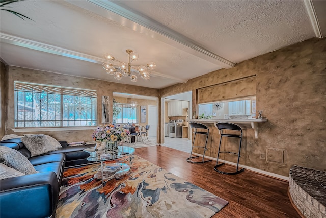 living room with beamed ceiling, wood-type flooring, a textured ceiling, and an inviting chandelier