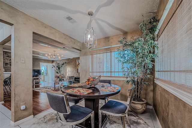 tiled dining area with a textured ceiling and a chandelier