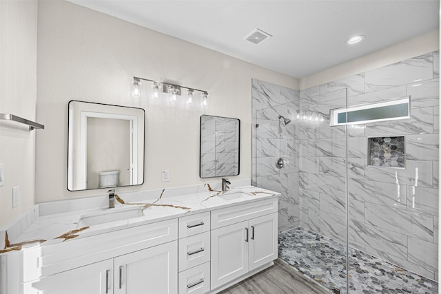 bathroom with tiled shower, wood-type flooring, and vanity