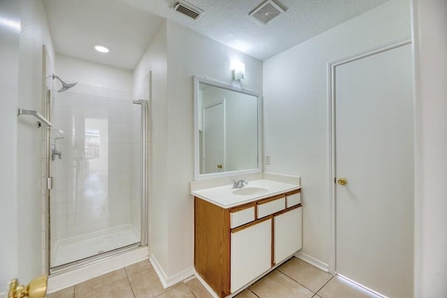 bathroom featuring a textured ceiling, vanity, tile patterned floors, and a shower with door