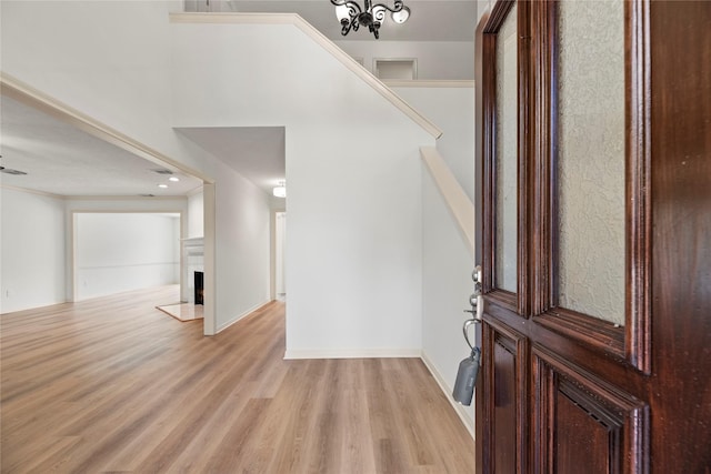 entrance foyer with light hardwood / wood-style floors, crown molding, and a notable chandelier