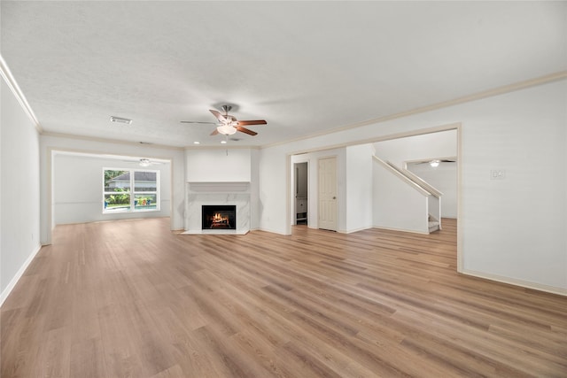 unfurnished living room featuring a textured ceiling, ceiling fan, crown molding, light hardwood / wood-style flooring, and a premium fireplace