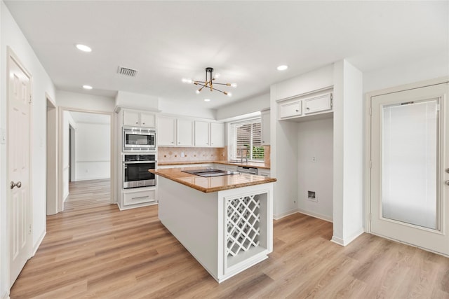 kitchen featuring stainless steel appliances, tasteful backsplash, light hardwood / wood-style flooring, a chandelier, and white cabinets