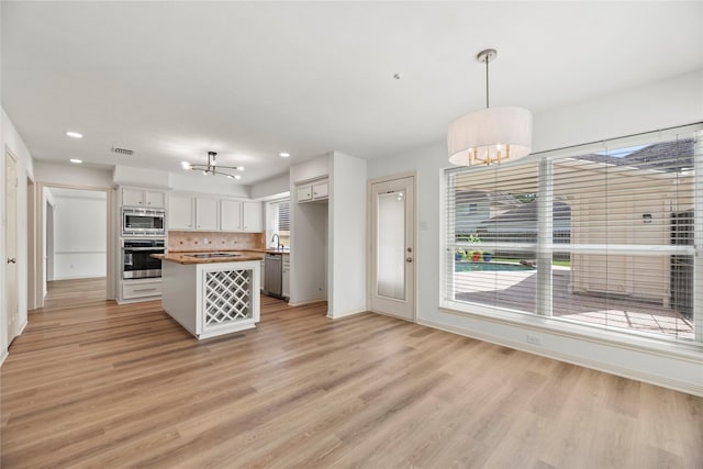 kitchen with wood counters, appliances with stainless steel finishes, a chandelier, white cabinetry, and hanging light fixtures