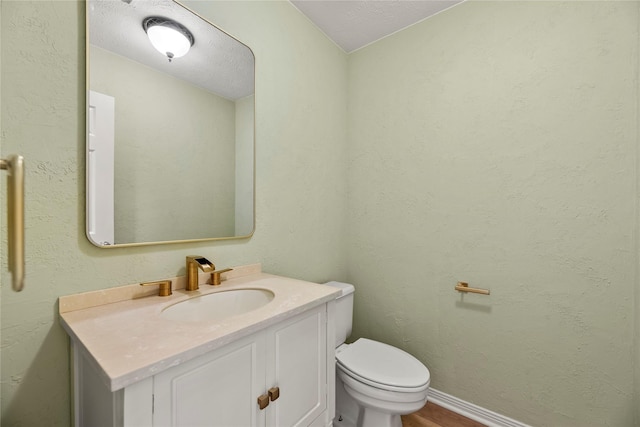 bathroom with vanity, toilet, and a textured ceiling