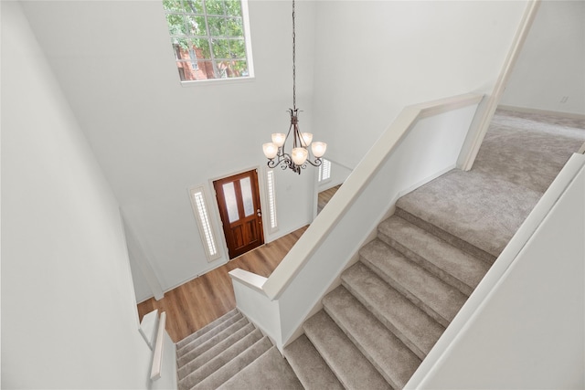 stairs with wood-type flooring and a notable chandelier