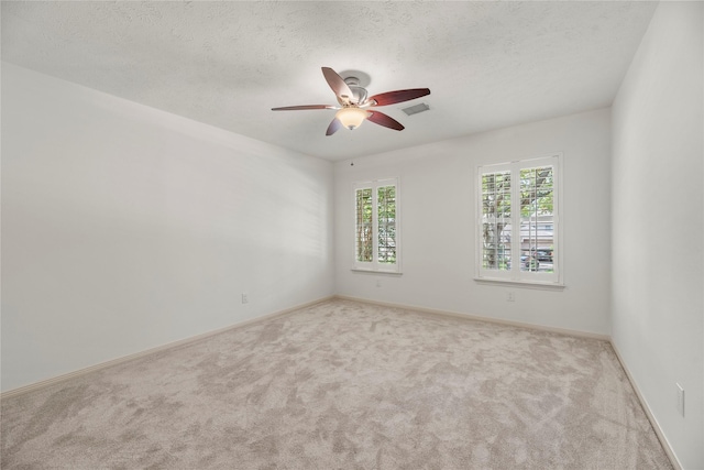 carpeted empty room featuring ceiling fan and a textured ceiling