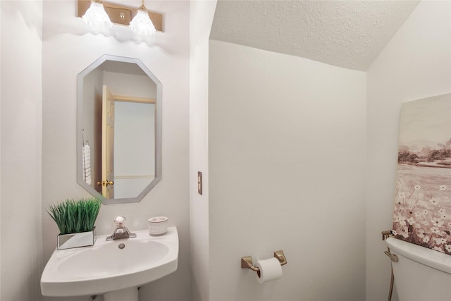 bathroom featuring toilet, sink, a textured ceiling, and vaulted ceiling