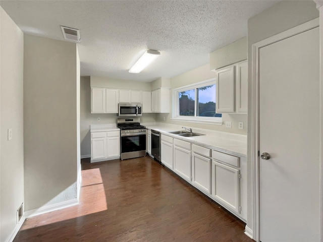 kitchen featuring dark hardwood / wood-style flooring, a textured ceiling, stainless steel appliances, sink, and white cabinets