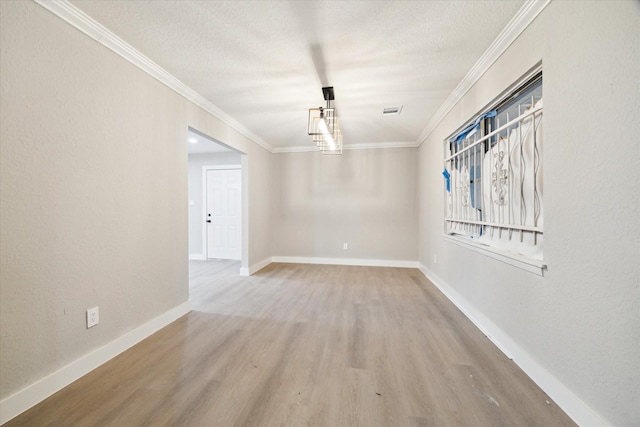 empty room with wood-type flooring, a textured ceiling, and ornamental molding