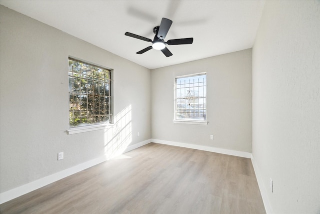 spare room featuring light wood-type flooring, ceiling fan, and a healthy amount of sunlight