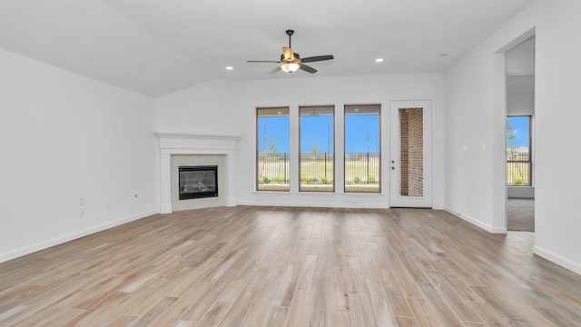 unfurnished living room with a glass covered fireplace, plenty of natural light, light wood-style flooring, and baseboards